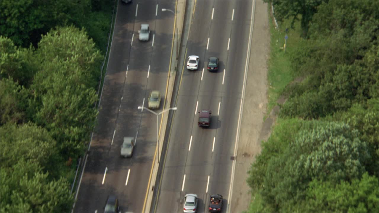 布朗克斯河公园道路的航拍图。汽车和越野车在树木环绕的公园道路上行驶。可以是freeway或highway。视频素材