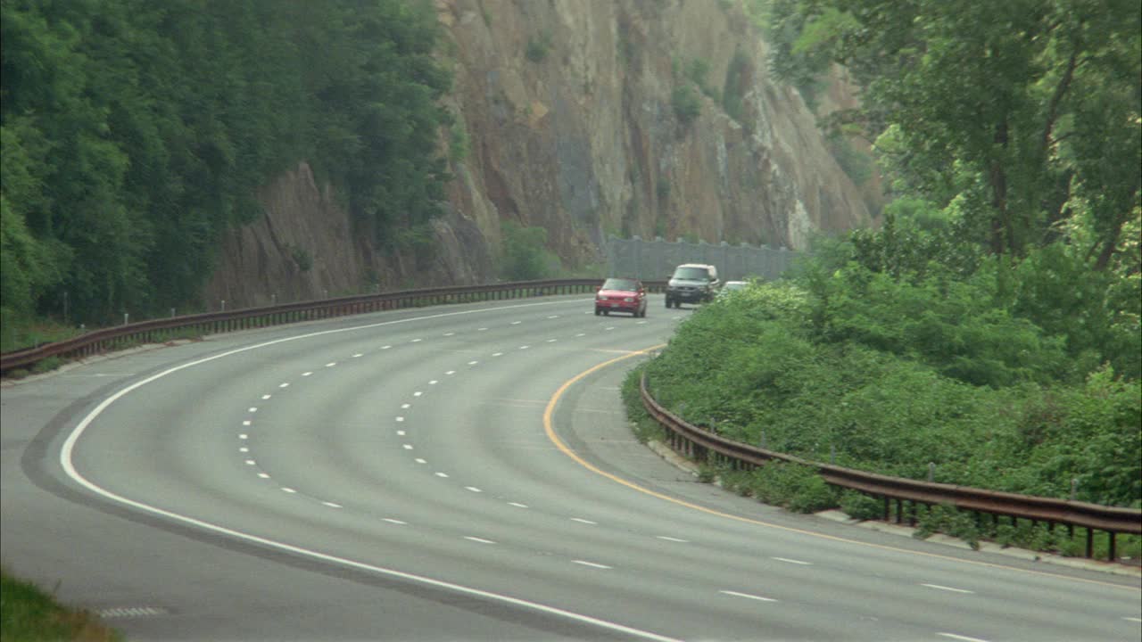 从左到右行驶在公园路、高速公路或高速公路上。轿车和越野车。湖泊、河流和路边的树木。可能在纽约州北部。视频下载