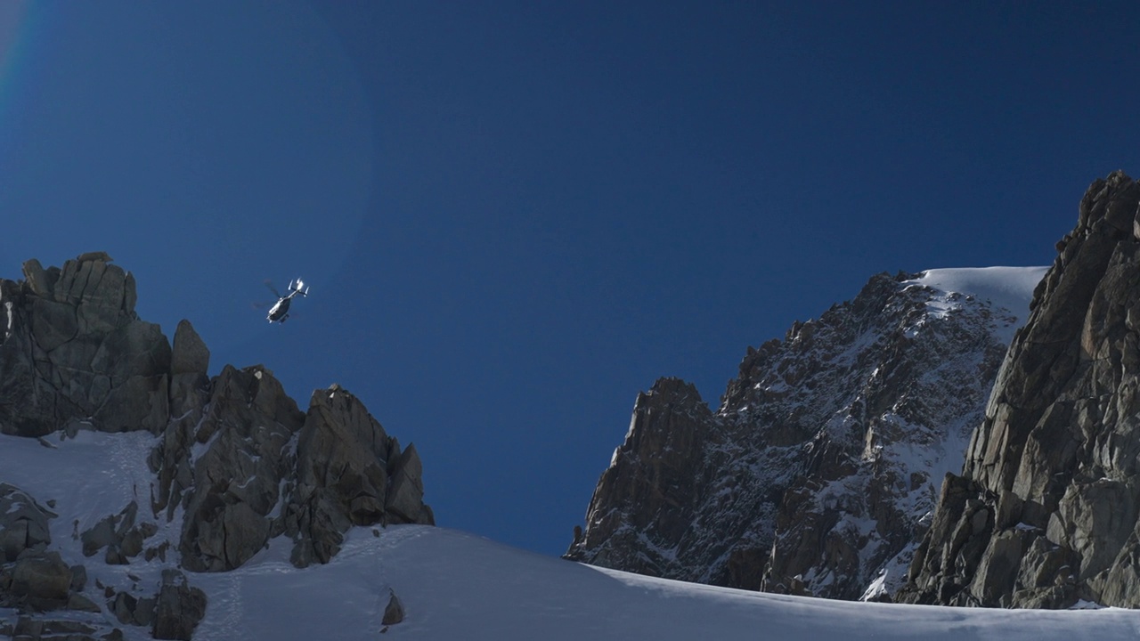 直升飞机在高海拔山脉上空飞行。白雪覆盖的尖峰视频素材