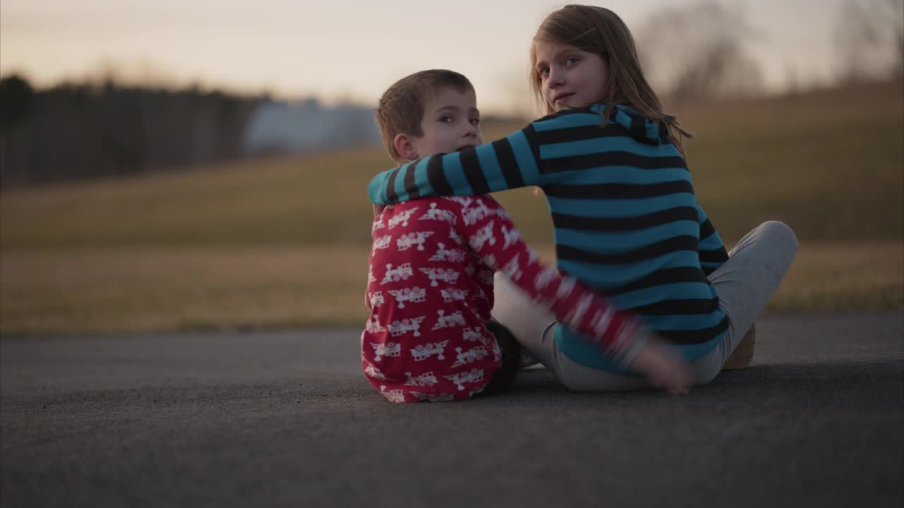 残疾男孩和姐姐拥抱坐在车道上视频素材