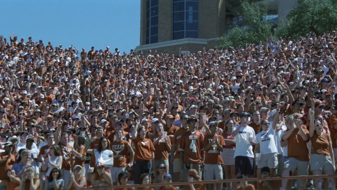 广角德克萨斯大学的球迷或观众在燃烧的橙色站在体育场。体育馆的灯光。足球比赛。达雷尔k.皇家体育场。人群欢呼。视频素材