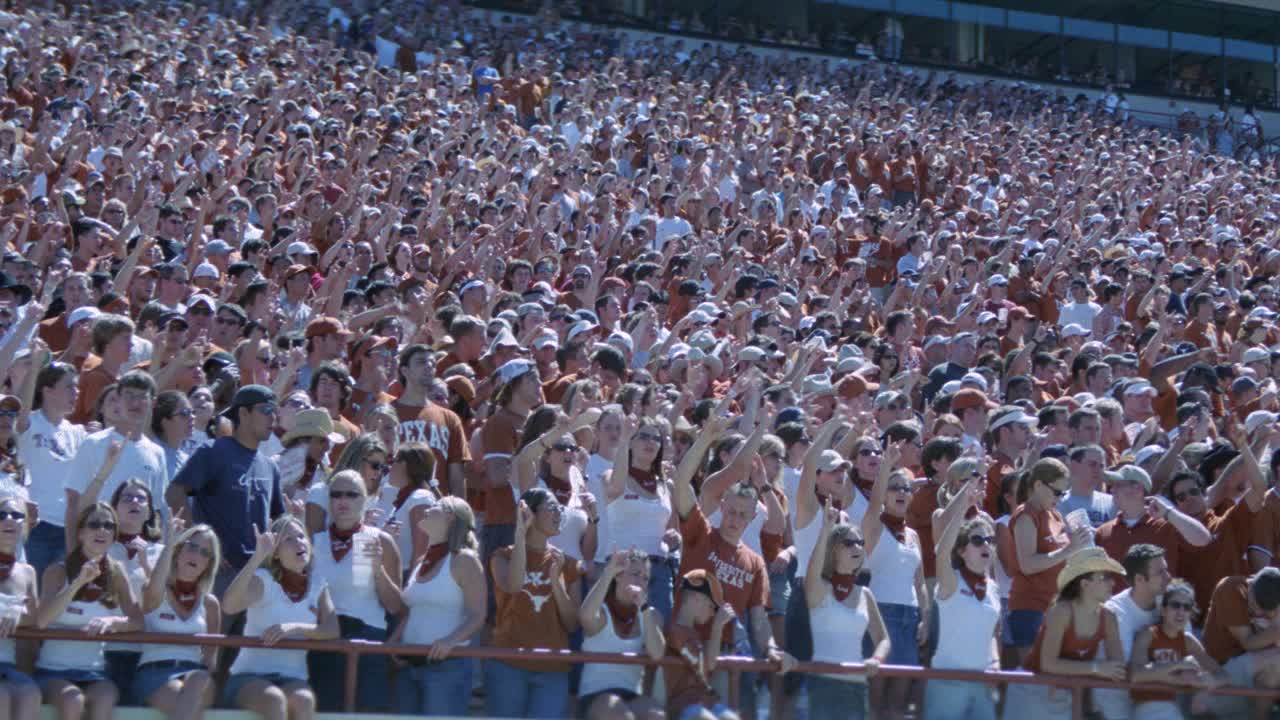 广角德克萨斯大学的球迷或观众在燃烧的橙色站在体育场。体育馆的灯光。足球比赛。达雷尔k.皇家体育场。人群欢呼。视频素材