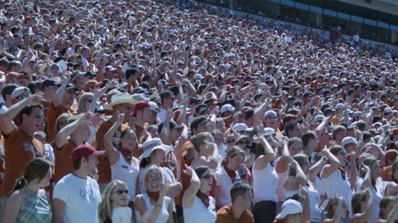 中角德克萨斯大学的球迷或观众站在燃烧的橙色体育场。摄像机左右平移。体育馆的灯光。足球比赛。达雷尔k.皇家体育场。人群欢呼。视频素材