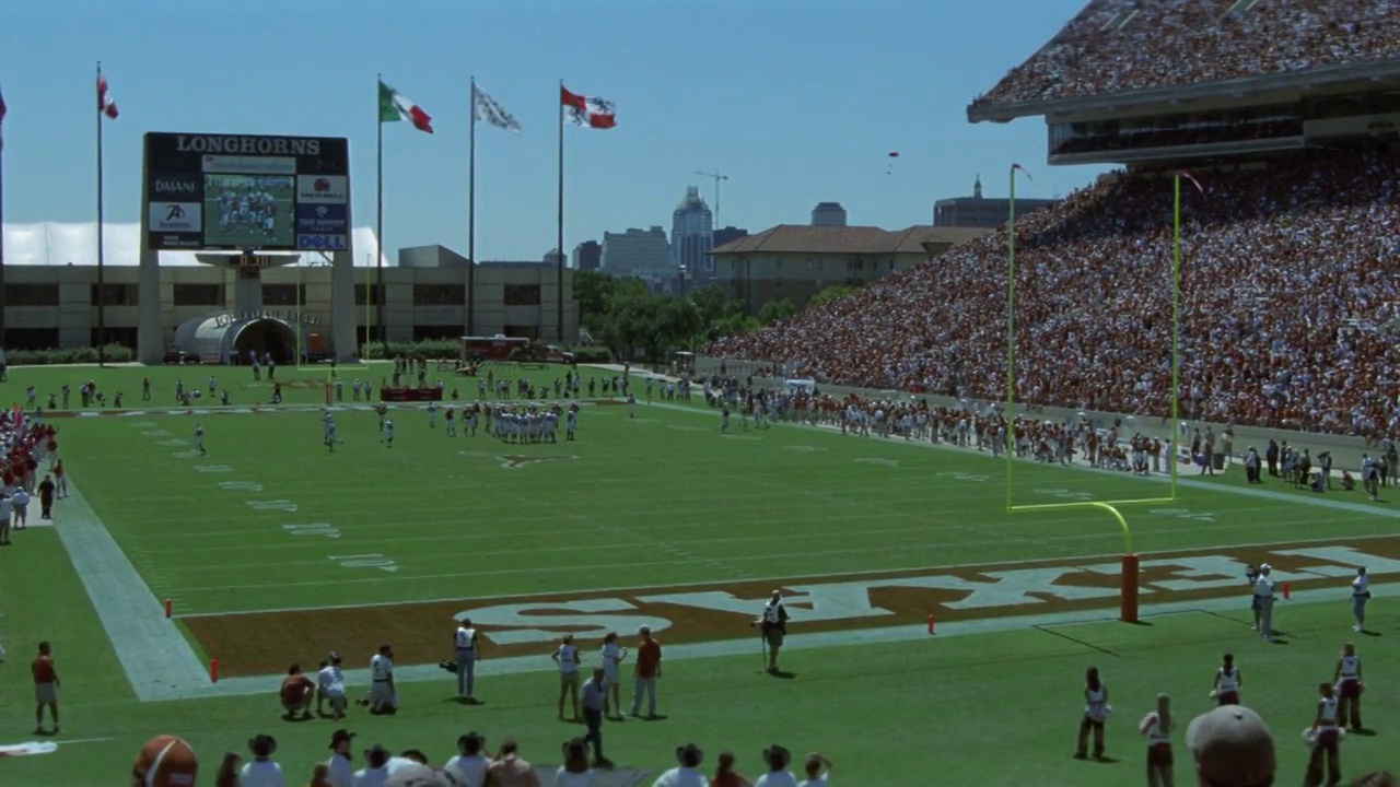 德克萨斯大学橄榄球队的广角在达雷尔k.皇家纪念体育场比赛。美国和德克萨斯州的国旗飘扬。BG的记分牌。在球场两边欢呼的人群或观众团队现场。结束区。视频素材