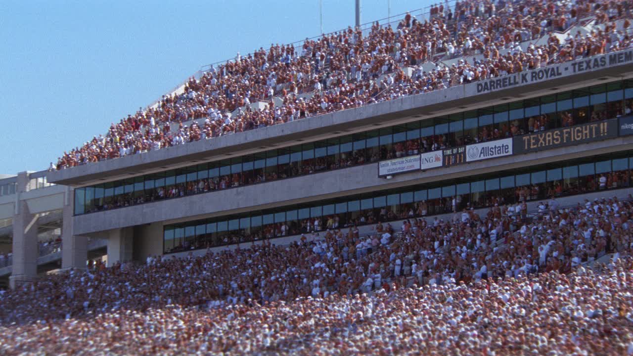 观看德克萨斯大学橄榄球比赛的观众或球迷在体育场欢呼的角度。达雷尔k.皇家纪念体育场。人群的欢呼声。观众上方的迷你记分板。视频素材