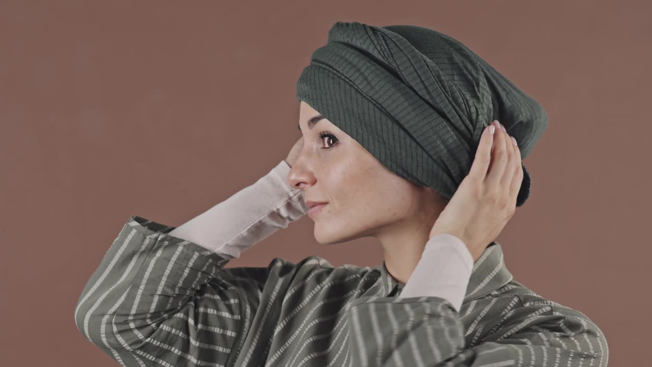 漂亮的穆斯林妇女修理头巾和对着镜头微笑视频下载