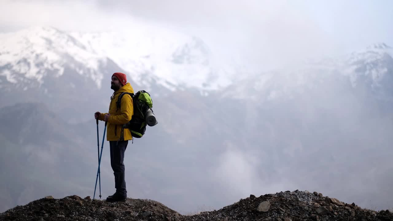 男子登山者站在山顶的山腰上视频素材