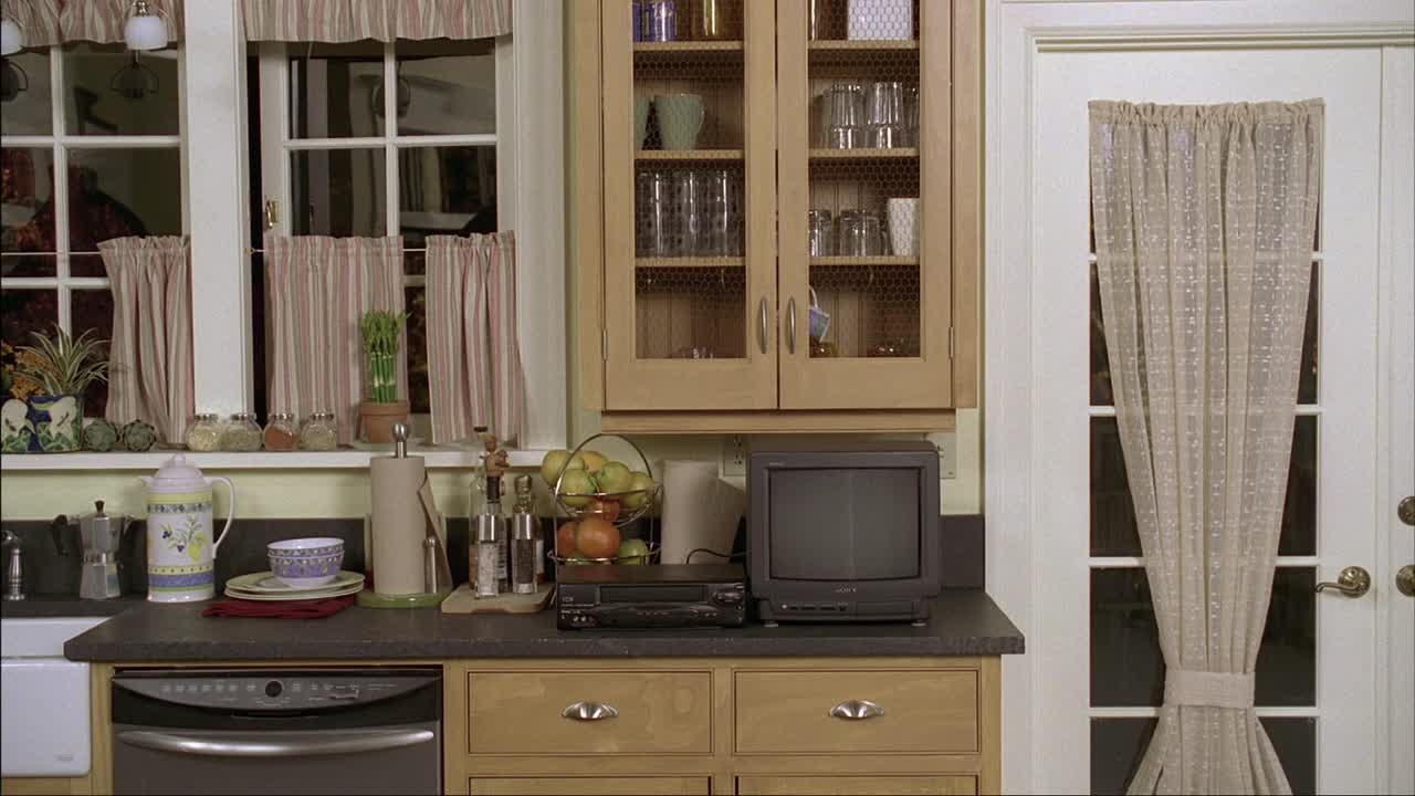 中档厨房的中档角度。橱柜中可见的盘子。窗户和窗帘。洗碗机和电视机。门和窗帘。视频下载