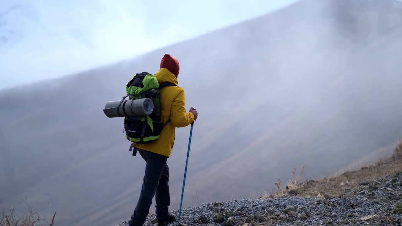 男子登山者站在山顶的山腰上视频下载