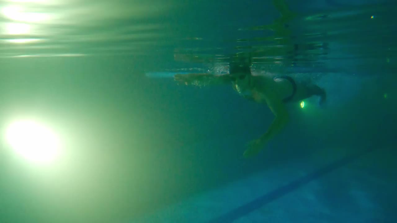 一名戴着防水眼镜、留着胡子的年轻男子在水下游泳——他的脚从侧面推开，转身回到跑道上视频下载