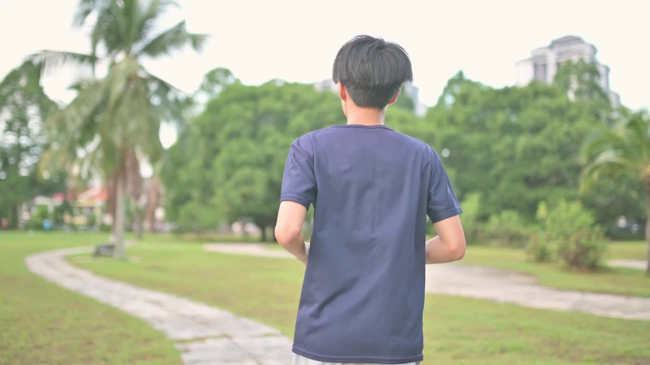 亚洲中国少年在公园慢跑独自在周末的早晨视频素材