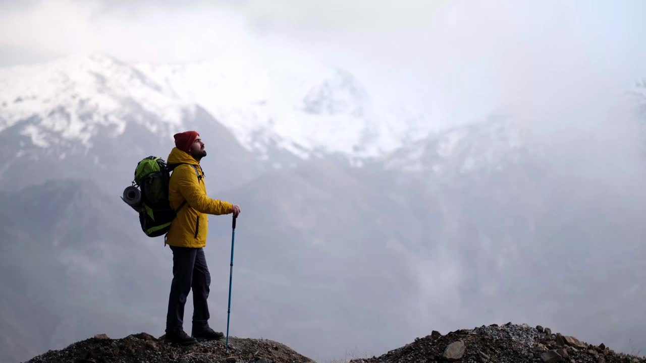 男子登山者站在山顶的山腰上视频素材