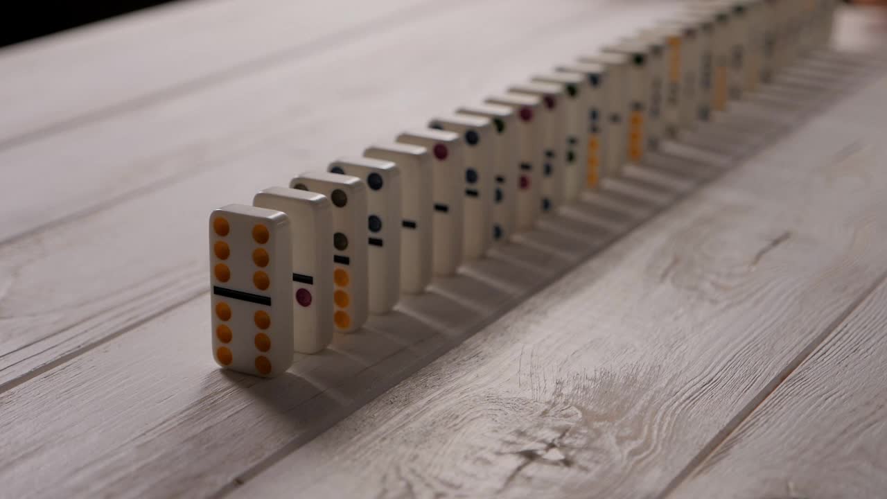 白色多米诺骨牌骰子与彩色点落在一个轻木制背景。视频素材