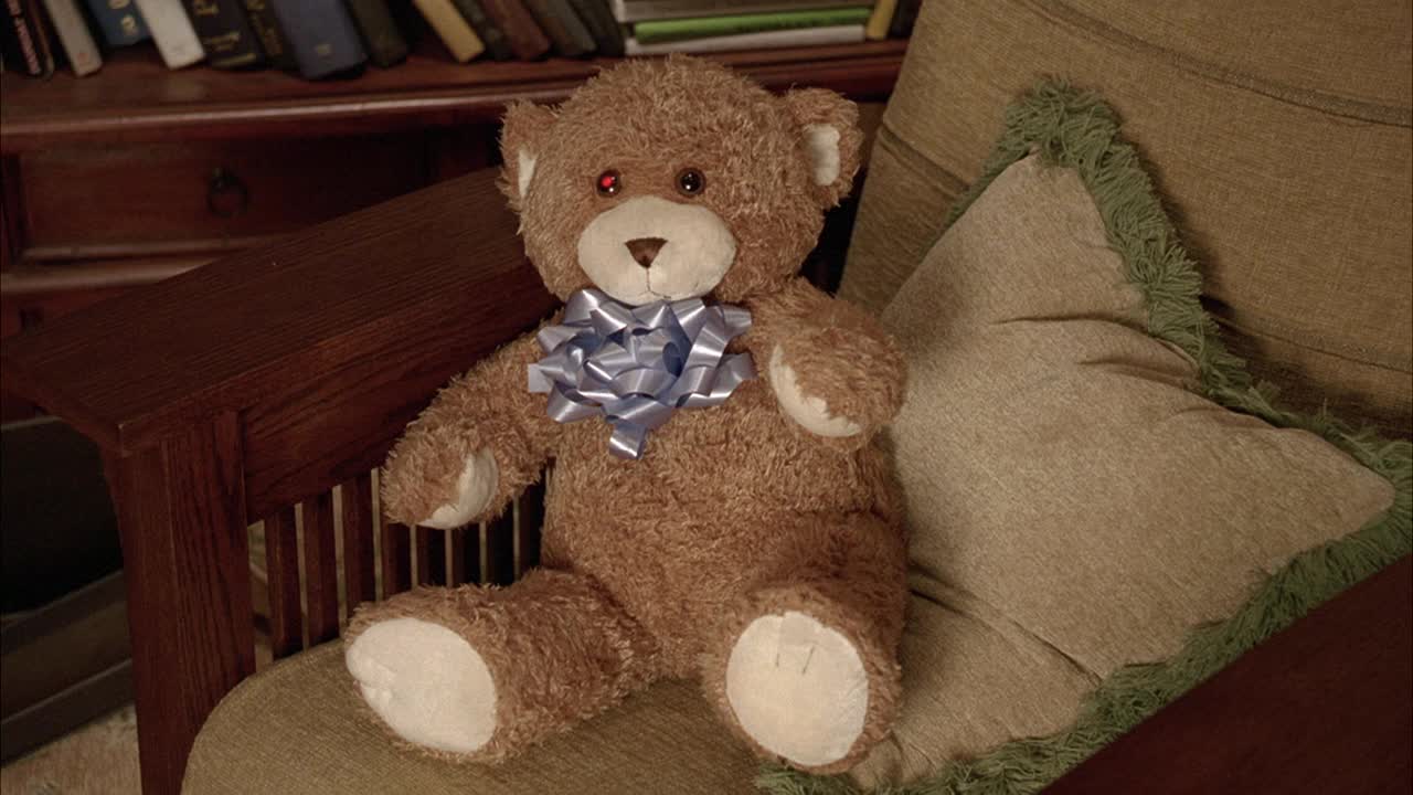 泰迪熊与弓坐在椅子上的近角度。可能是托儿所或客厅。玩具。毛绒玩具。视频下载