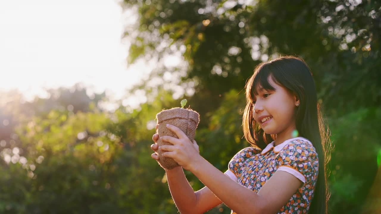 可爱的小女孩把小植物送给阳光。幸福新生命拯救地球和生态系统的理念。视频下载
