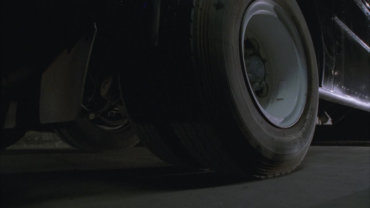 卡车或商用车后轮的中等角度，由车轴两侧的双轮和泥浆护板显示。车辆逆转。视频素材