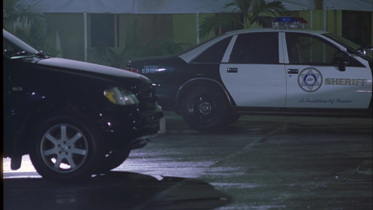 警车驶过停车场的特写镜头。可能是警察局。警车在bg可见。suv上的闪光灯或bizbar。一辆越野车驶出停车场。路面光滑。可能是因为下雨。视频素材