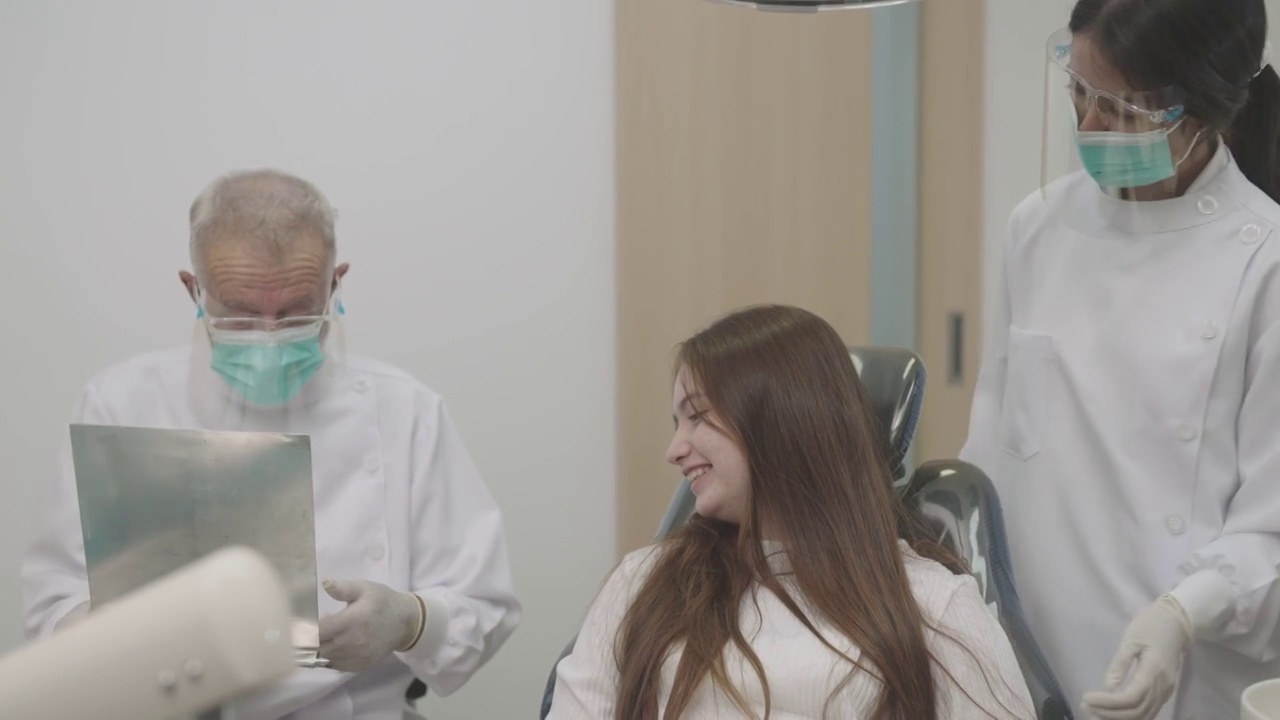十几岁的女孩在牙医那里检查牙齿。可爱的女孩坐在牙科椅上接受牙科治疗。视频下载
