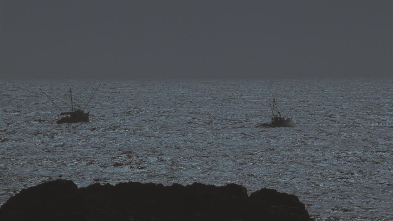 大洋中两艘渔船的广角拍摄。沿海岸线的岩石。36 FPS。视频素材