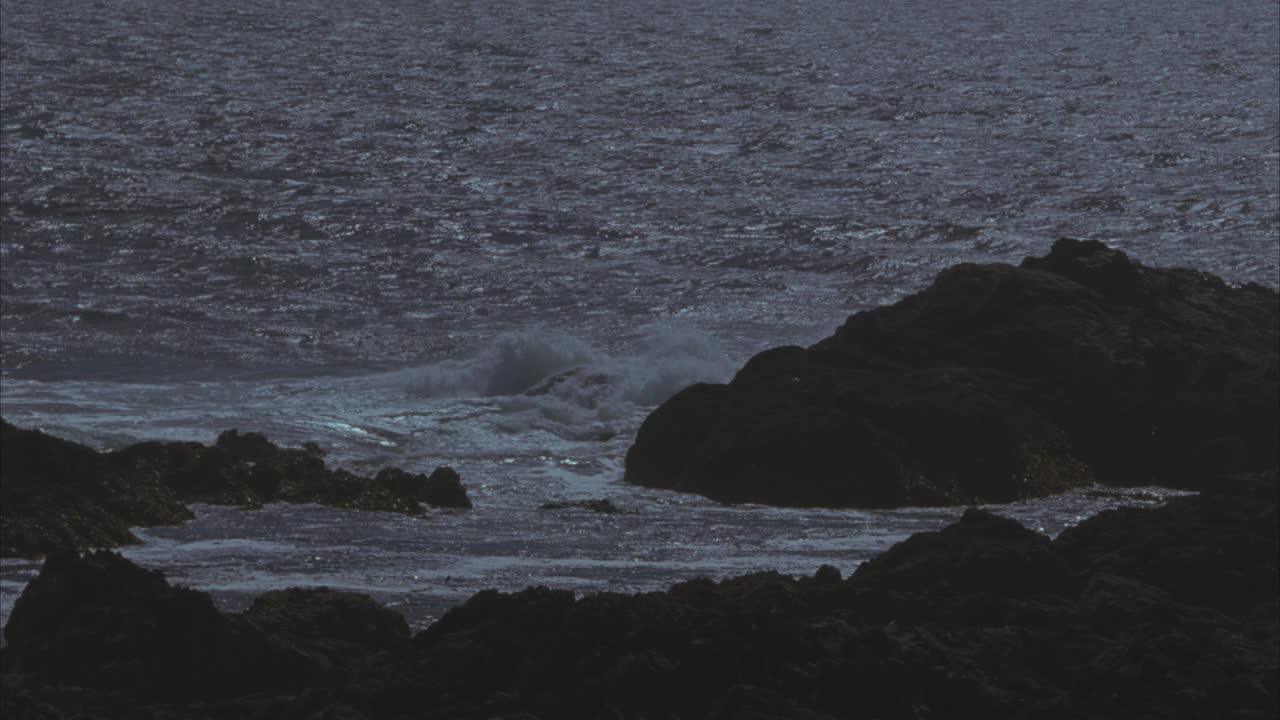 海浪沿崎岖的海岸线撞击岩石的中等角度。海洋。60 FPS。视频素材