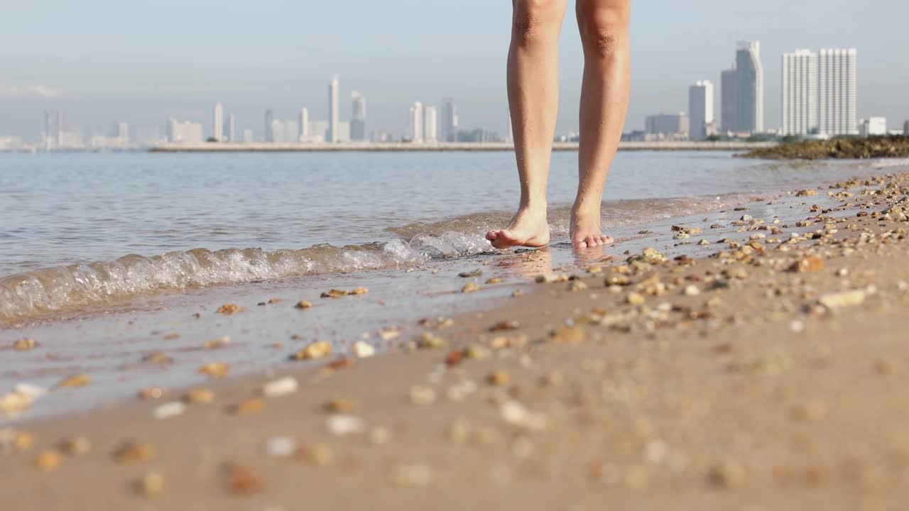 4K视频慢镜头近距离步行在海滩上远离大城市的背景。视频素材