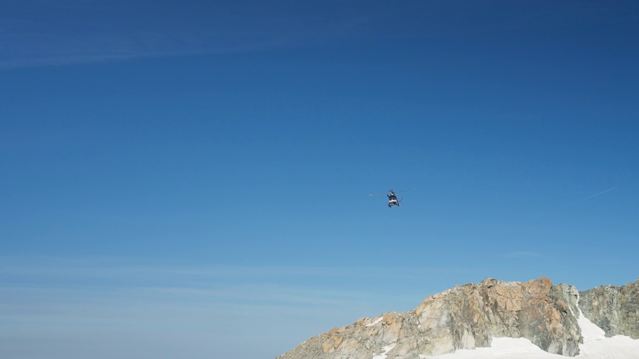 直升飞机在高海拔山脉上空飞行。白雪覆盖的尖峰视频素材
