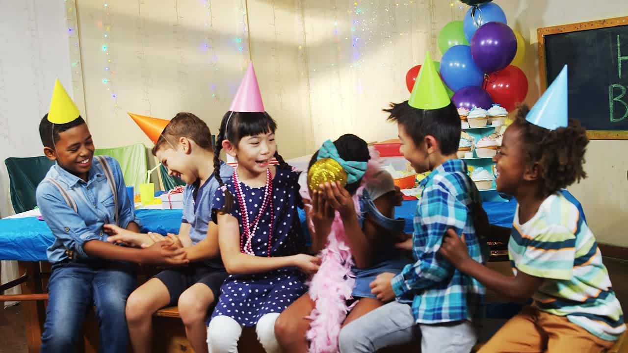 在生日派对上，五彩纸屑飘落在戴着派对帽子的孩子们身上视频素材