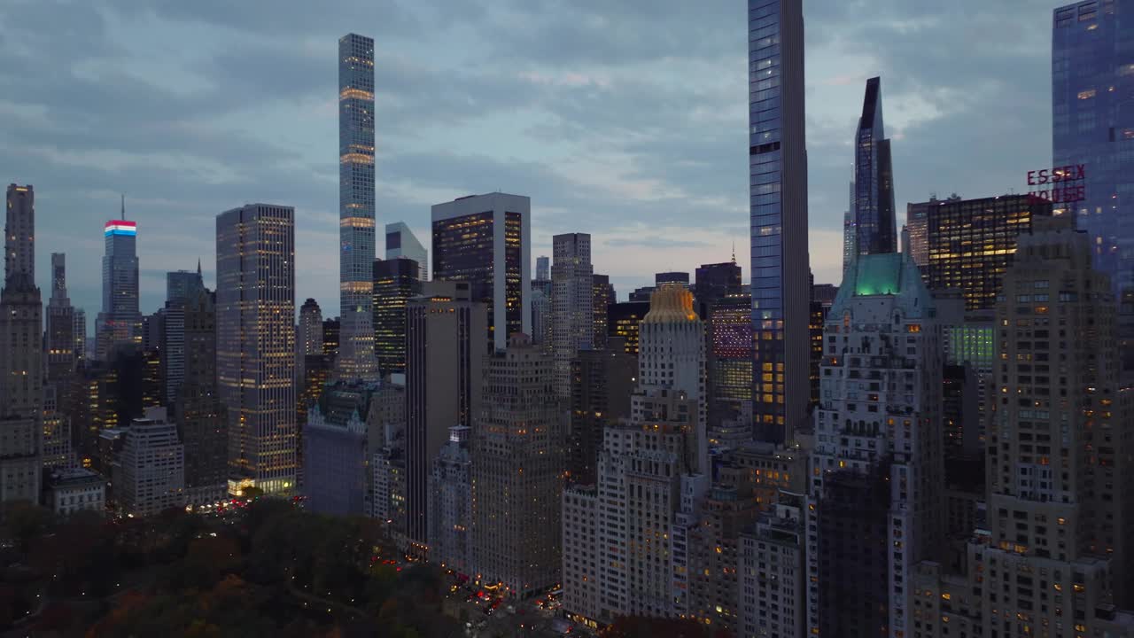 黄昏时分的市中心摩天大楼。在有明亮窗户的高层建筑上向前飞。曼哈顿，美国纽约市视频下载