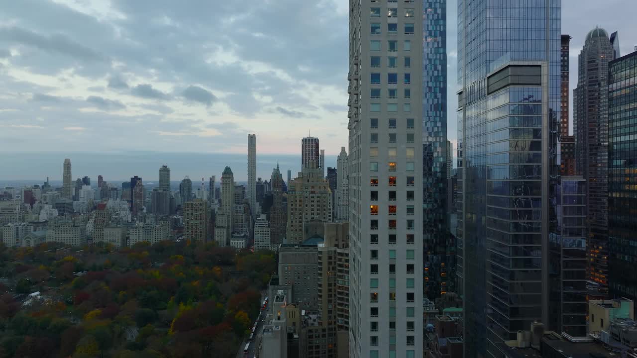 市中心高层建筑和通往中央公园的繁忙长街的滑梯和镜头。现代摩天大楼映照着黄昏的天空。曼哈顿，美国纽约市视频下载