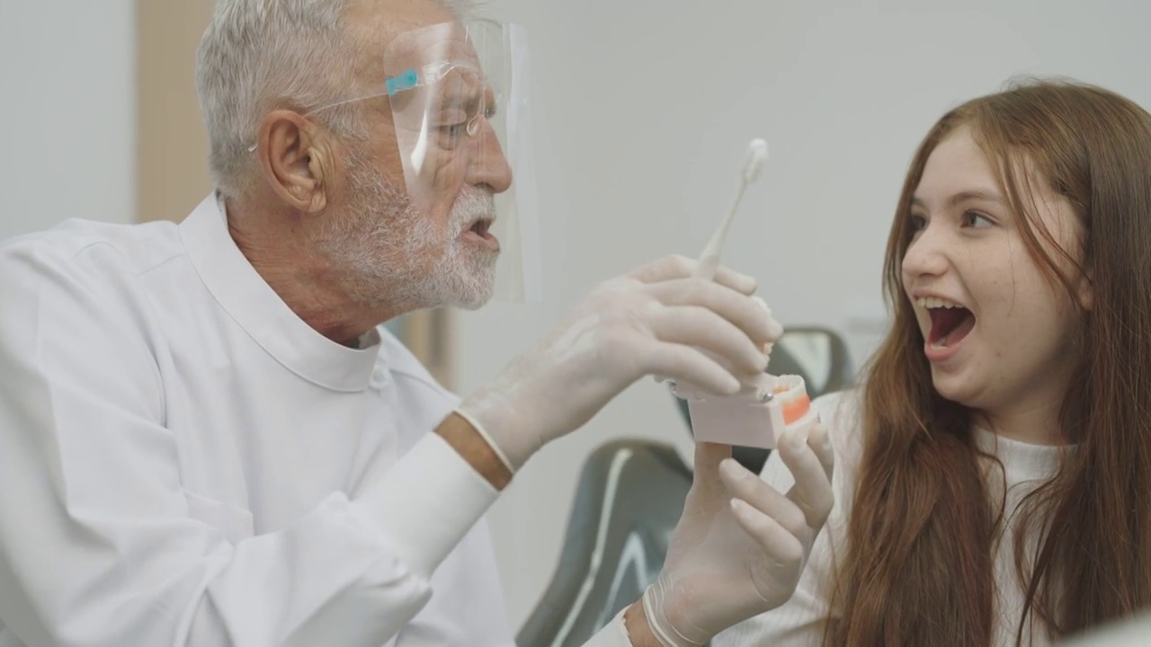 十几岁的女孩在牙医那里检查牙齿。可爱的女孩坐在牙科椅上接受牙科治疗。视频下载