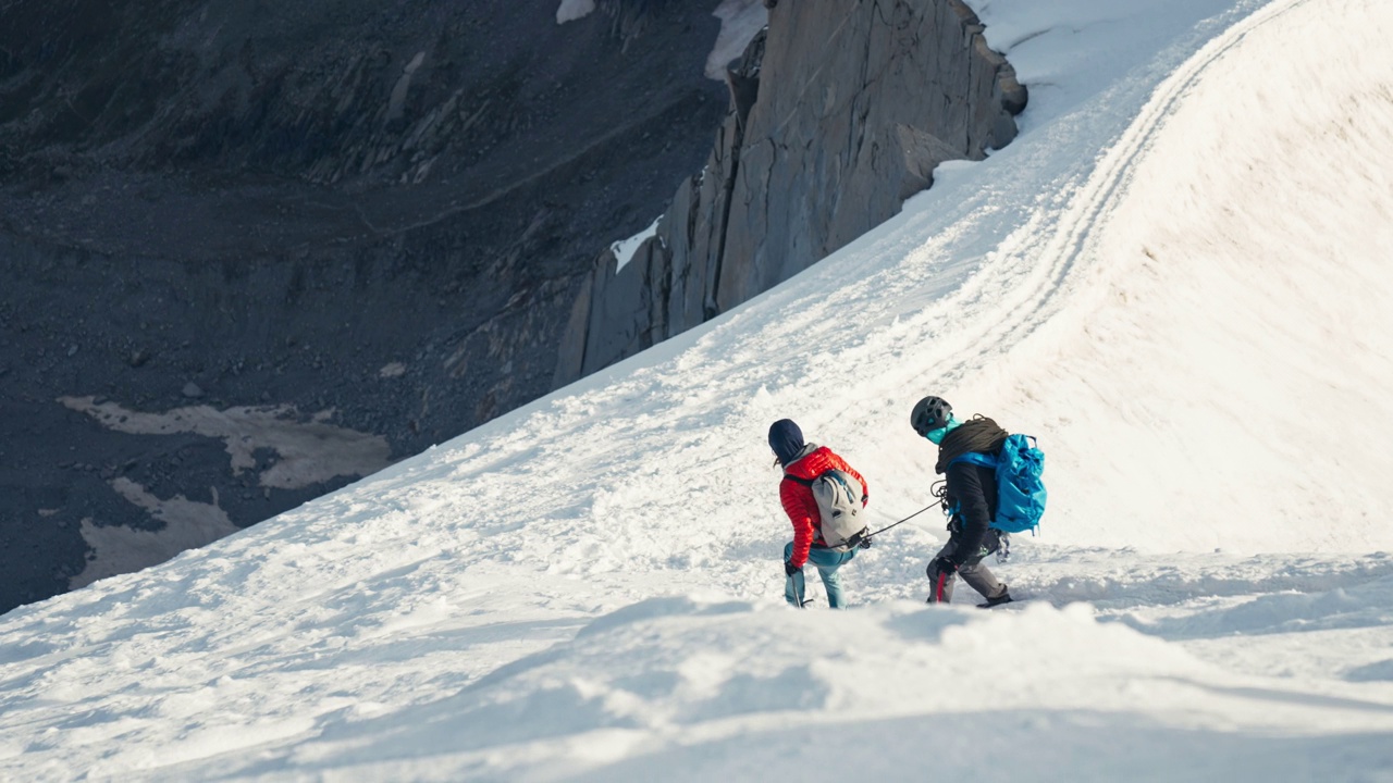 一队登山者正在从陡峭的山峰上下来。冬天的风景视频下载