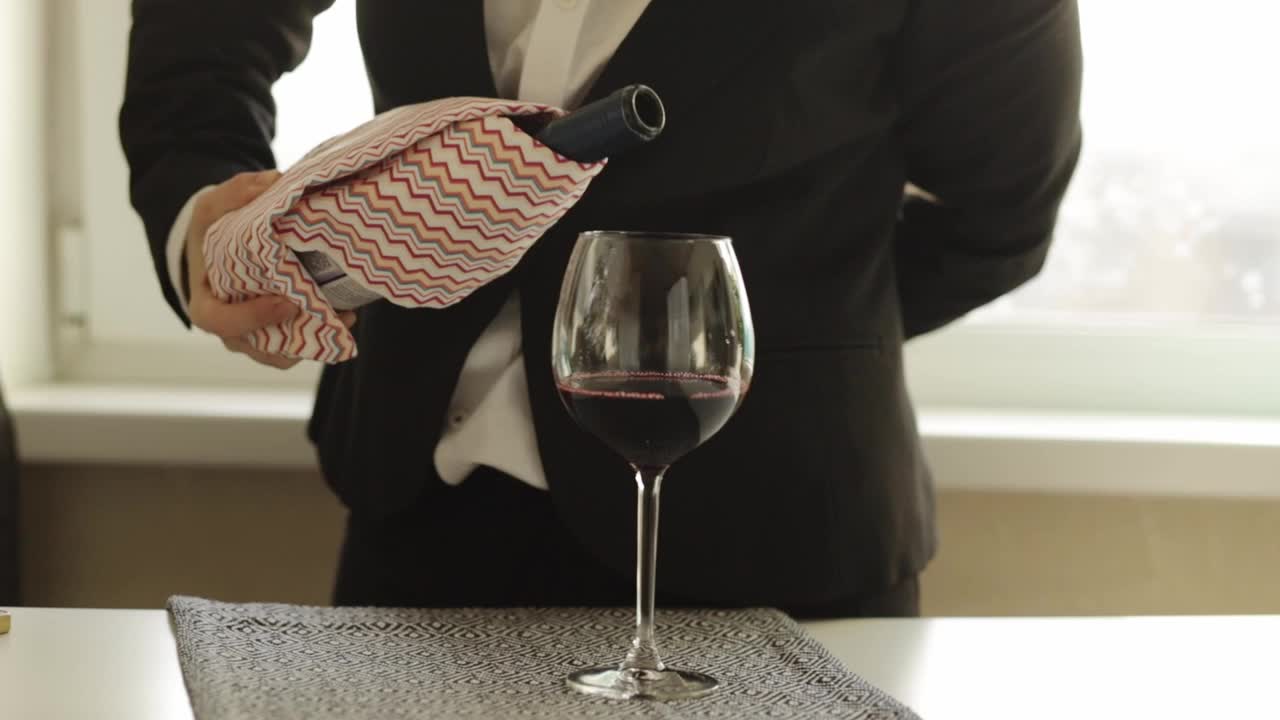 在餐厅的餐桌上，侍酒师把葡萄酒从瓶子里倒进玻璃杯里视频素材