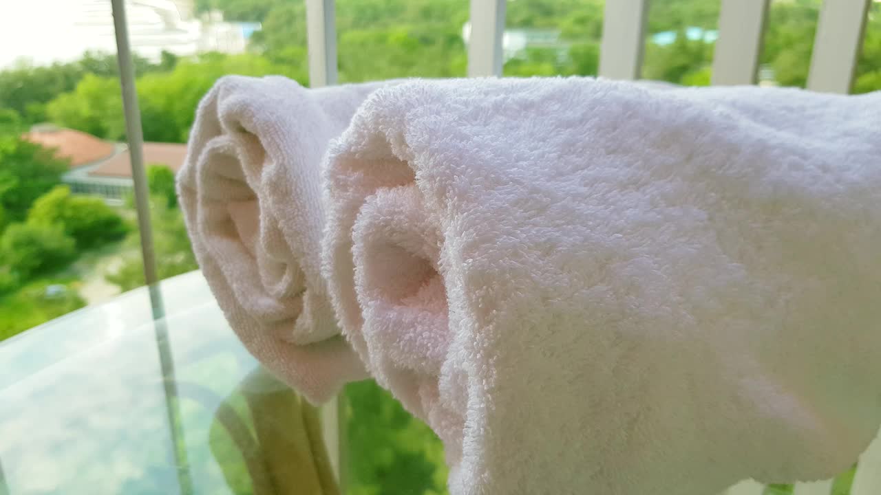 一个女人的手抚摸着两条折叠成一卷的柔软的白色毛巾的特写镜头视频下载