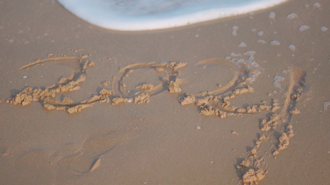 写在沙滩上，被海浪抹去的2021年特写。迎接2022年的新概念视频素材