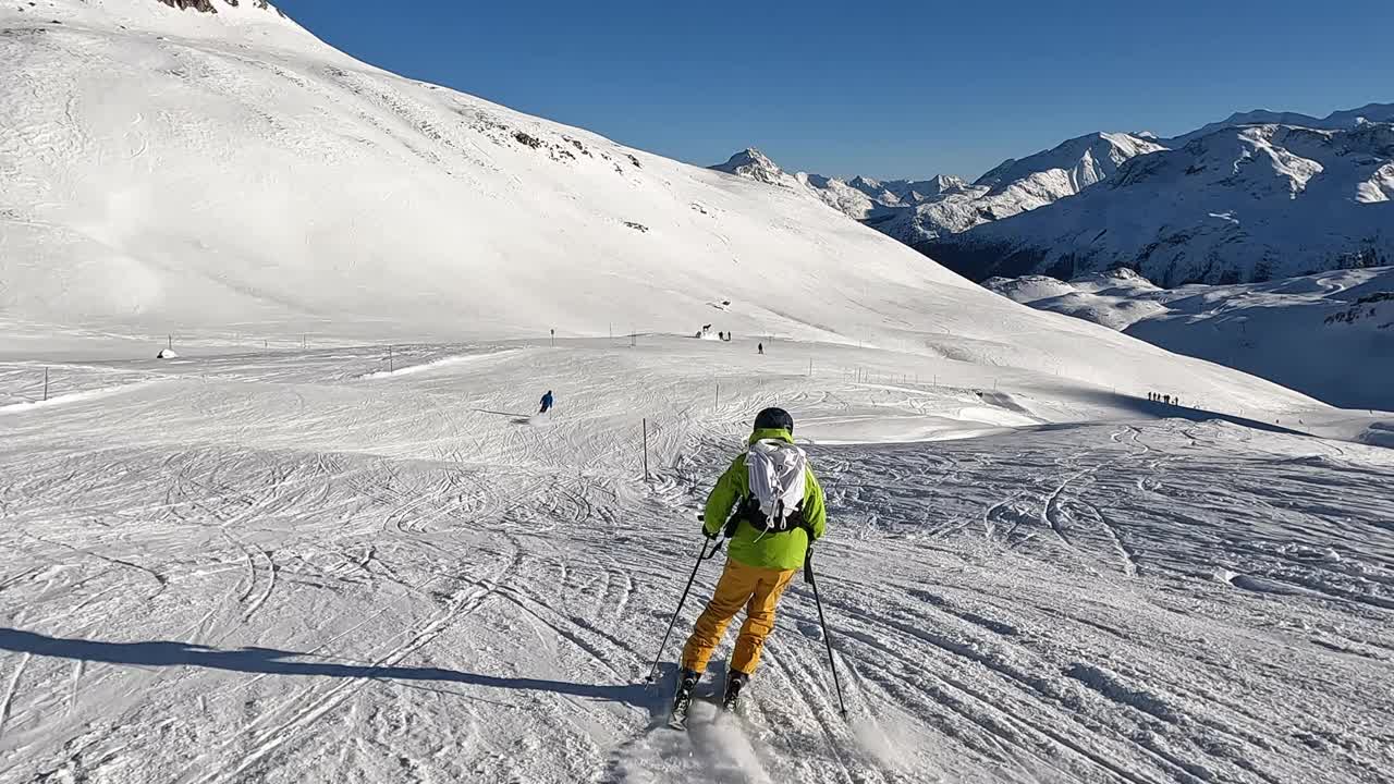慢镜头:一个年轻人在阿尔卑斯山的滑雪坡上滑下坡视频下载
