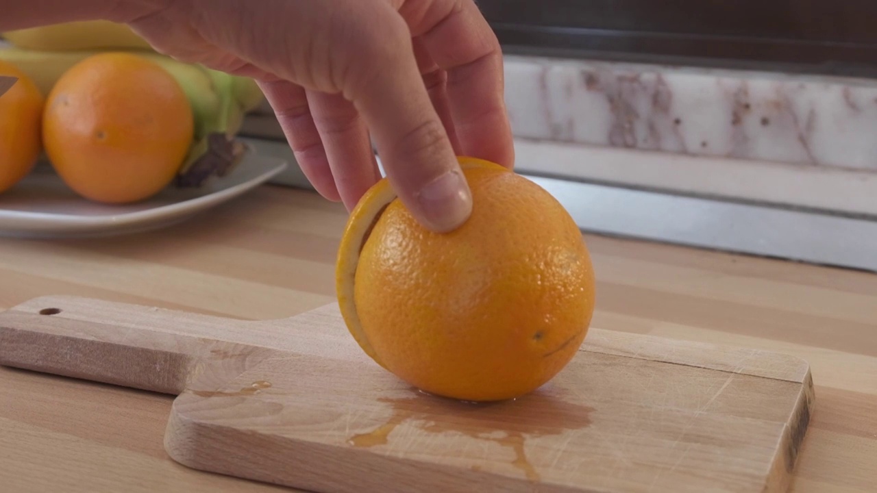 慢动作男手在木板上切下半个橘子视频素材