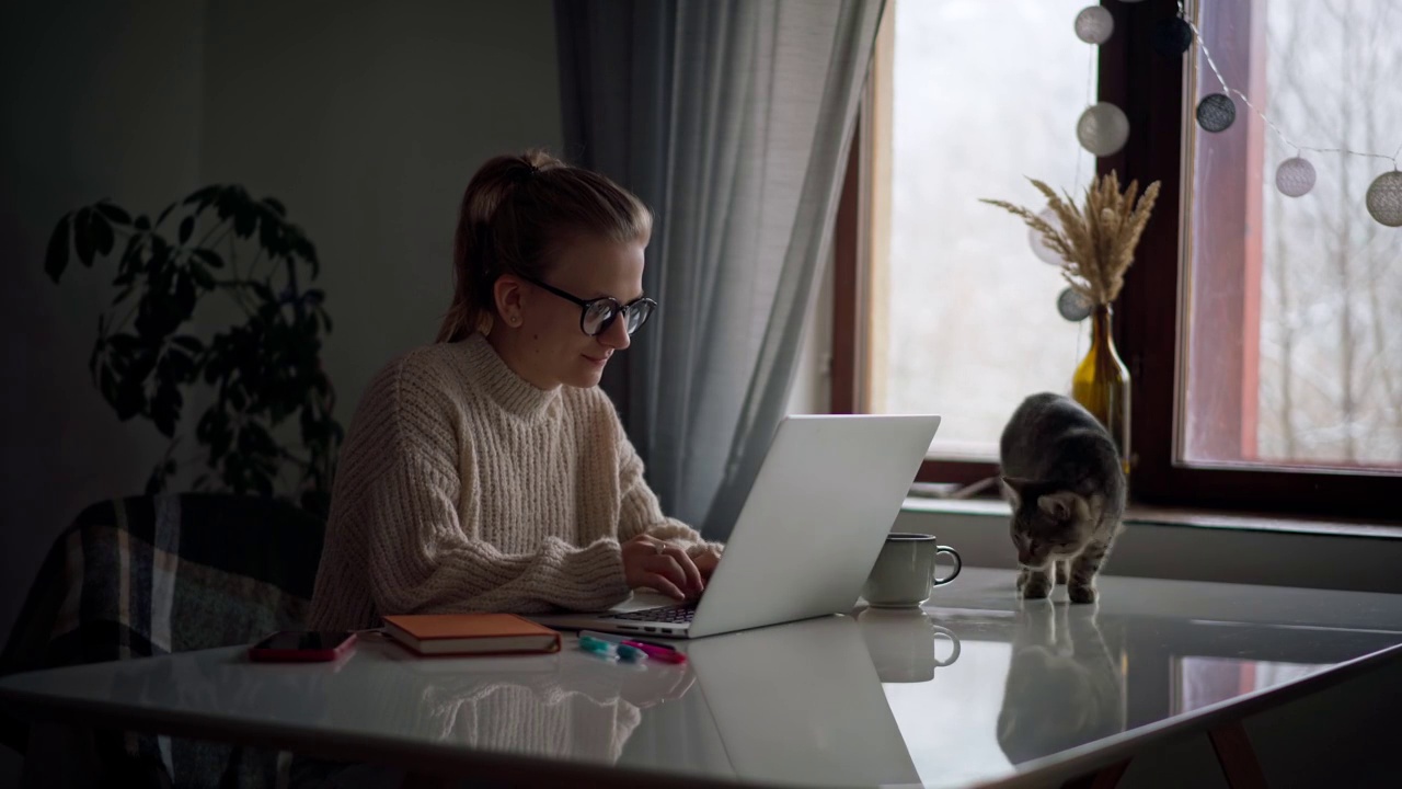 一个年轻女孩在家里工作或学习的时候在笔记本电脑上打字视频素材