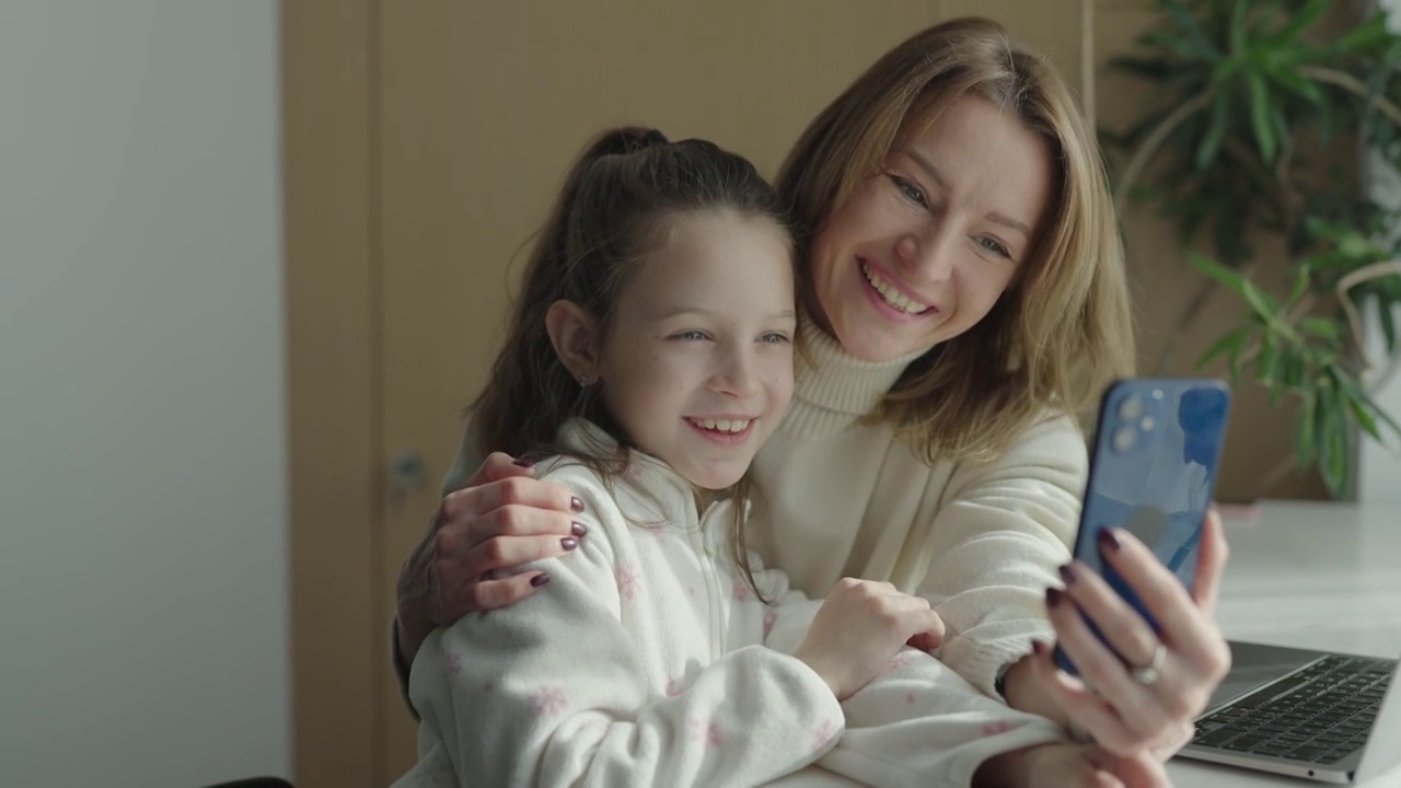 年轻快乐的母亲和可爱的女儿用智能手机进行视频聊天视频下载
