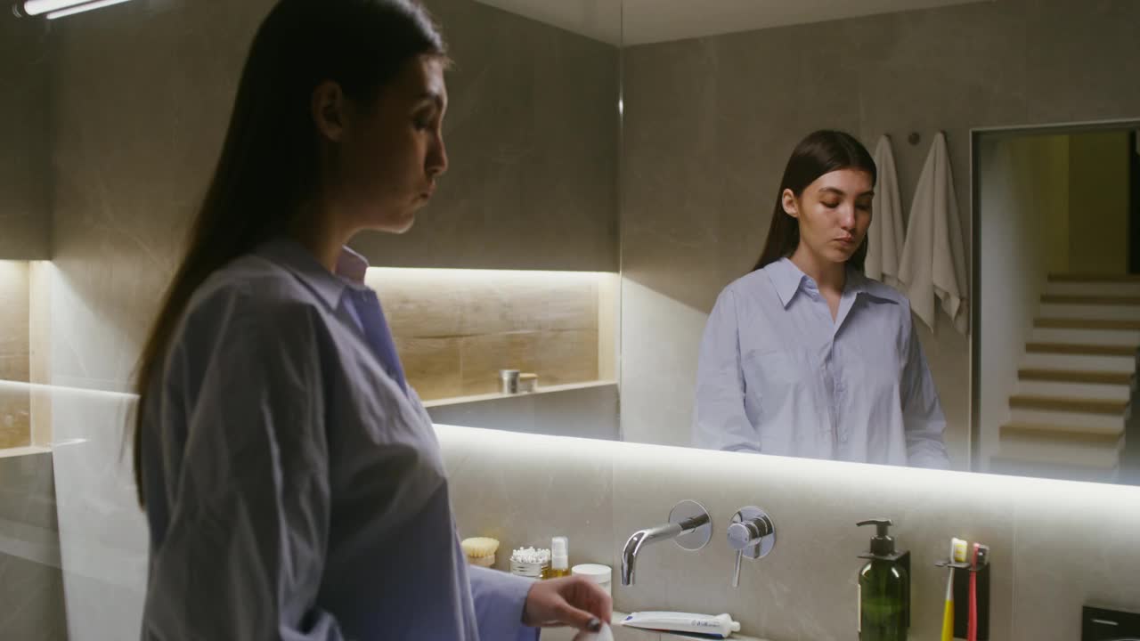 女人戴上织物保湿面膜，站在镜子前视频素材