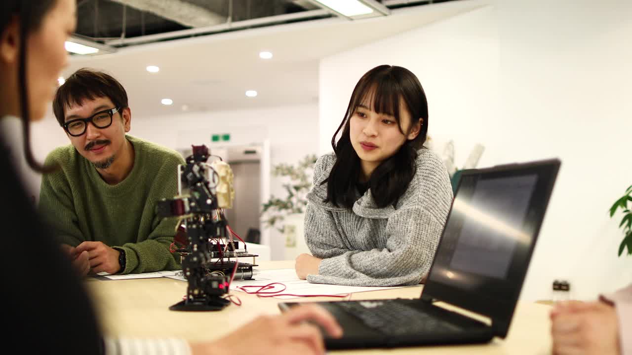 一位年轻的女工程师专心地听着机器人原型机的操作视频素材