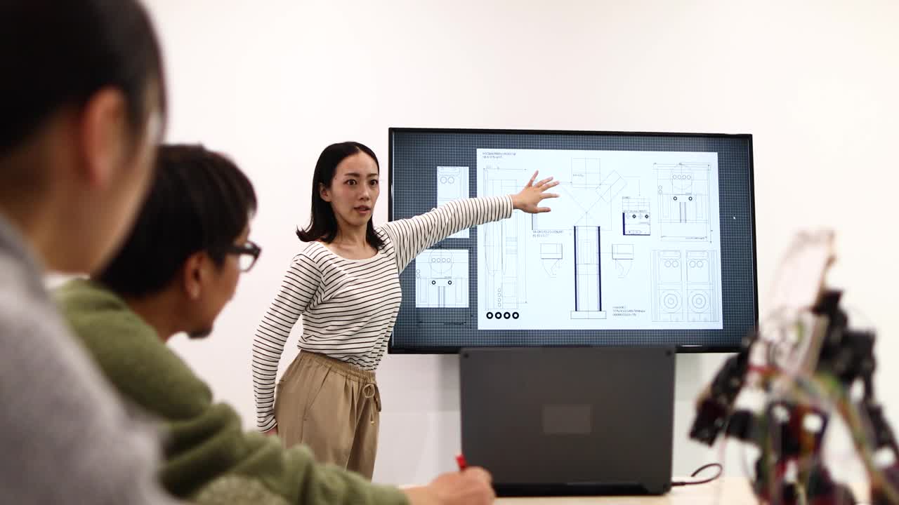 一位女性开发人员向团队成员展示人形机器人的蓝图视频素材