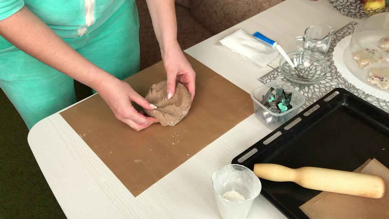 一位妇女用擀面杖擀开姜饼面团。制作雪花和星星形状的姜饼。总体规划。视频下载