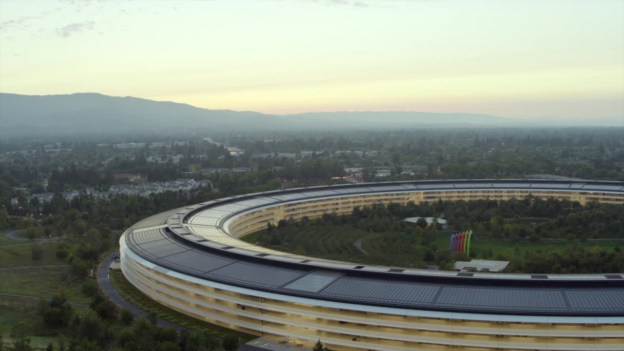 在加州库比蒂诺，黎明时分，天空缓缓盘旋着苹果总部大楼，背景是雾蒙蒙的山脉视频下载