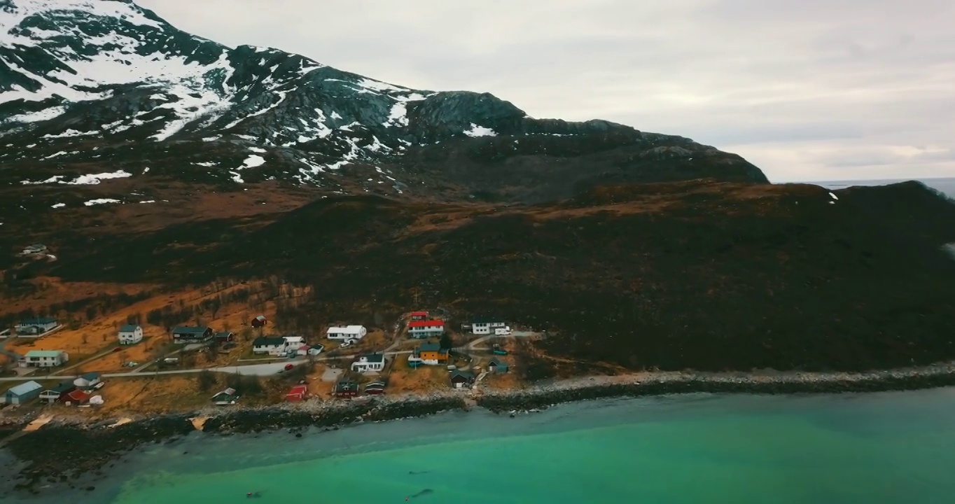 空中摇摄山景上房屋的美丽镜头，冬季无人机在海上飞行-挪威特罗姆瑟市视频下载