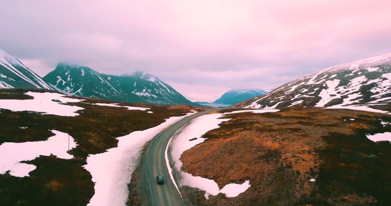 空中向上拍摄的汽车行驶在雪山景观-特罗姆瑟市，挪威视频下载