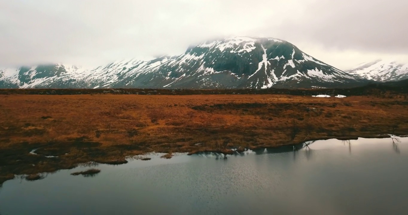 空中风景雪覆盖岩层在冬季，无人机飞行在宁静的湖-特罗姆瑟市，挪威视频下载