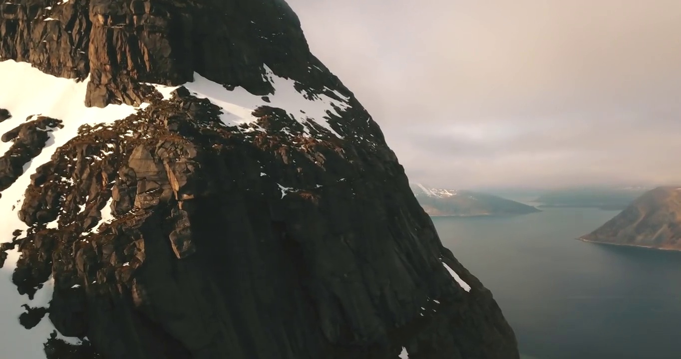 空中平移雪山岩层的风景镜头，无人机在海上的景观上空飞行-特罗姆瑟市，挪威视频下载