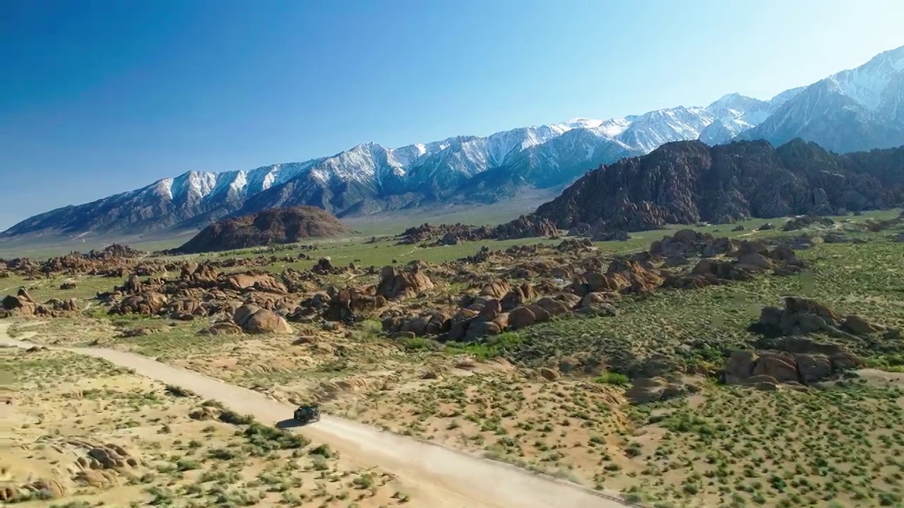 空中前进越野车移动在绿色的土地在阳光明媚的一天-塞拉，加利福尼亚视频素材