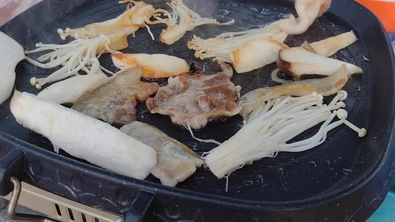 近距离拍摄的手烹饪烤五花肉在铁烧烤锅。视频下载