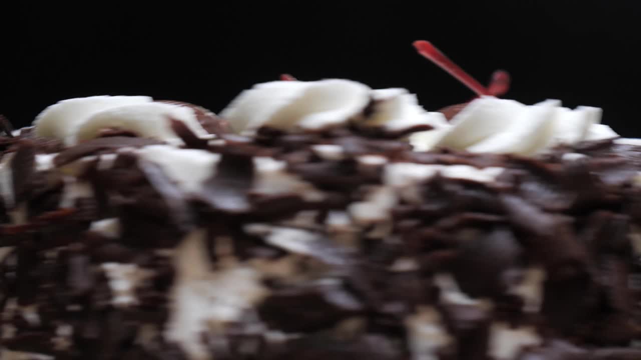 旋转黑巧克力蛋糕在黑色背景，慢动作。视频下载